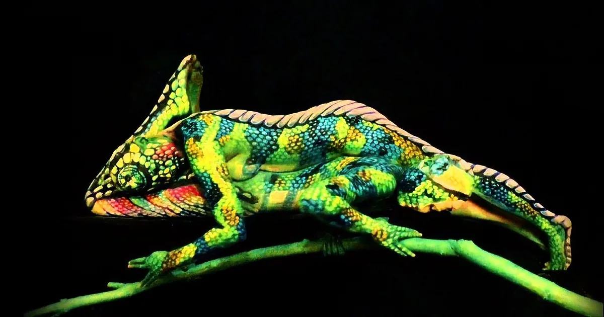 A vibrant, fluorescent green chameleon with yellow and blue spots is perched on a branch against a dark background.