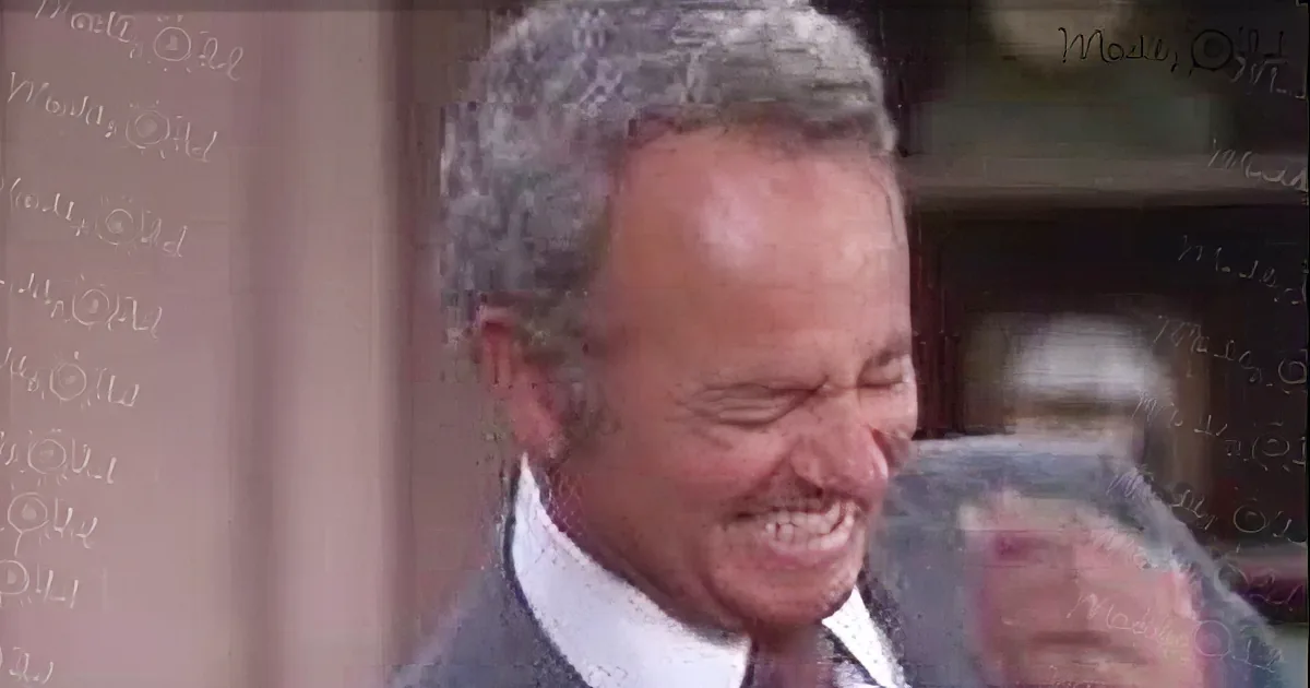 An older man in a suit and tie is laughing heartily, holding a glass of water.
