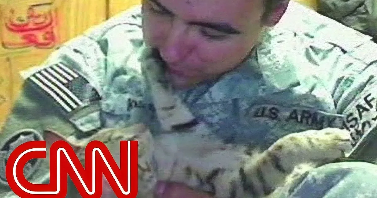 A soldier in a military uniform is holding a small object, with a CNN logo in the foreground.
