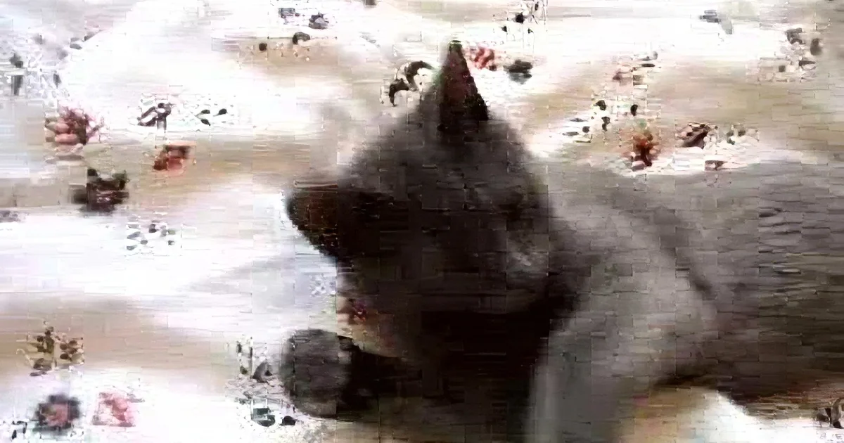 A gray cat is lying on a floral-patterned blanket, looking to the side with its head slightly tilted.