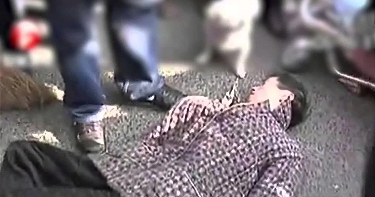 A person in black boots stands over a person lying on the ground, who appears to be injured or unconscious.