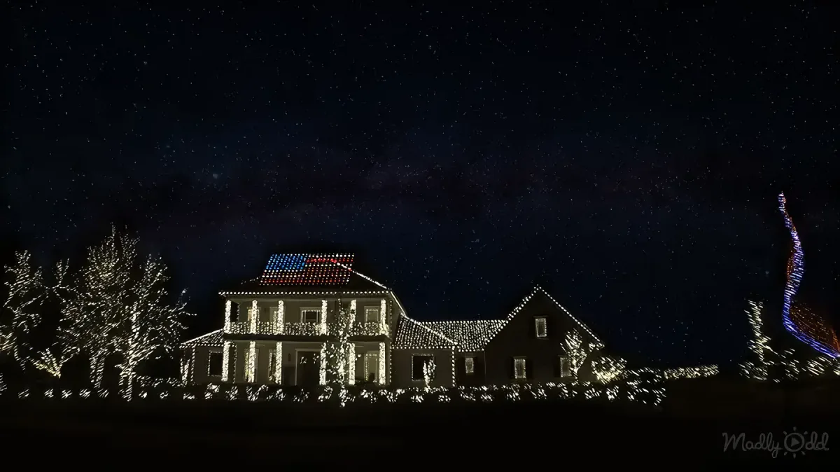 House with white Christmas lights. American flag on top.