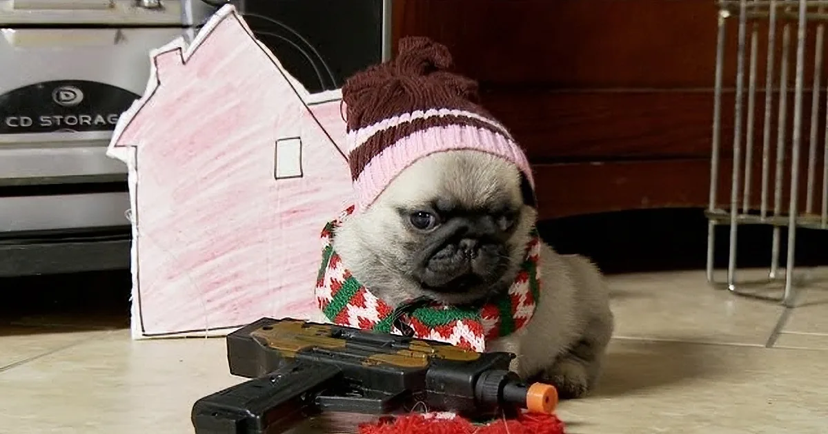 A pug wearing a festive sweater and hat is positioned next to a toy house and toy guns on a tiled floor.