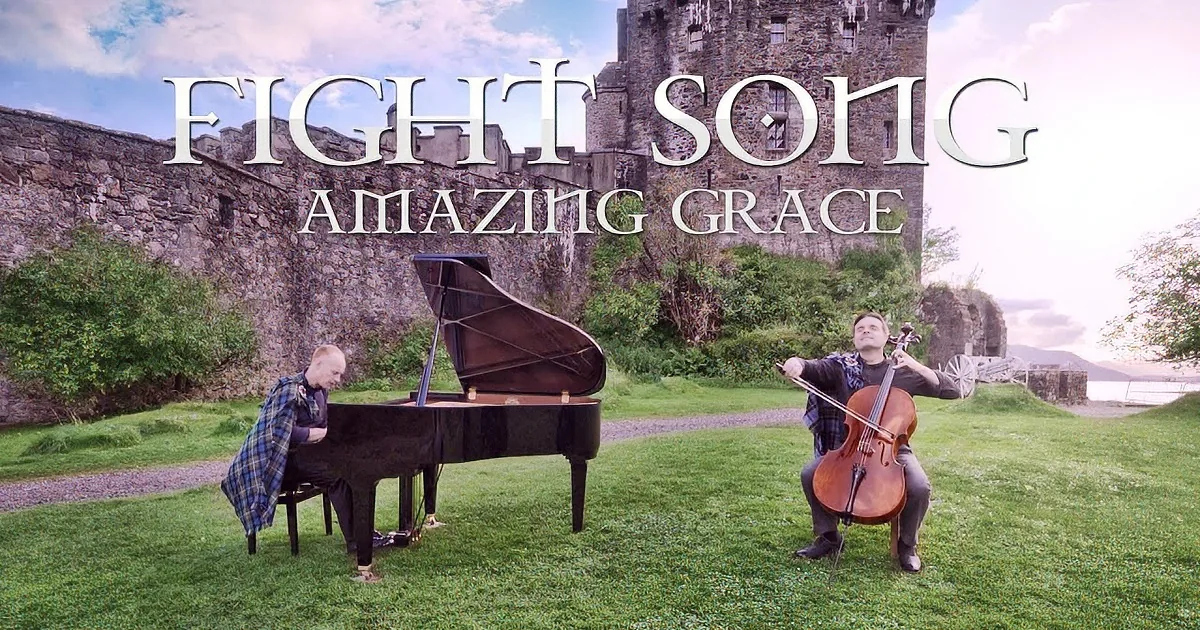 A man plays cello in front of a grand piano and another musician, with a castle backdrop and "Fight Song Amazing Grace" text.