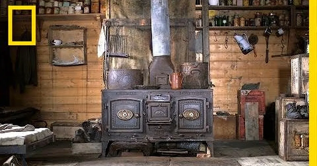 A rustic wood-burning stove with a large chimney and surrounding shelves filled with various items.