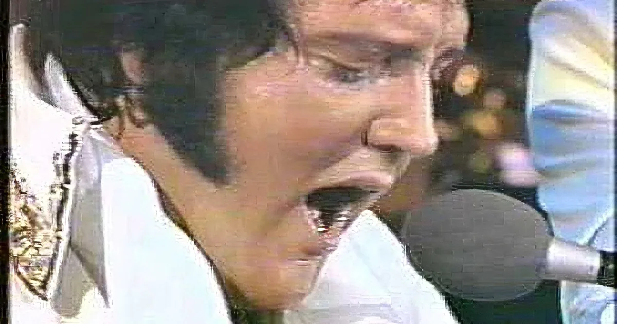 A close-up of a person in a white outfit singing into a microphone.