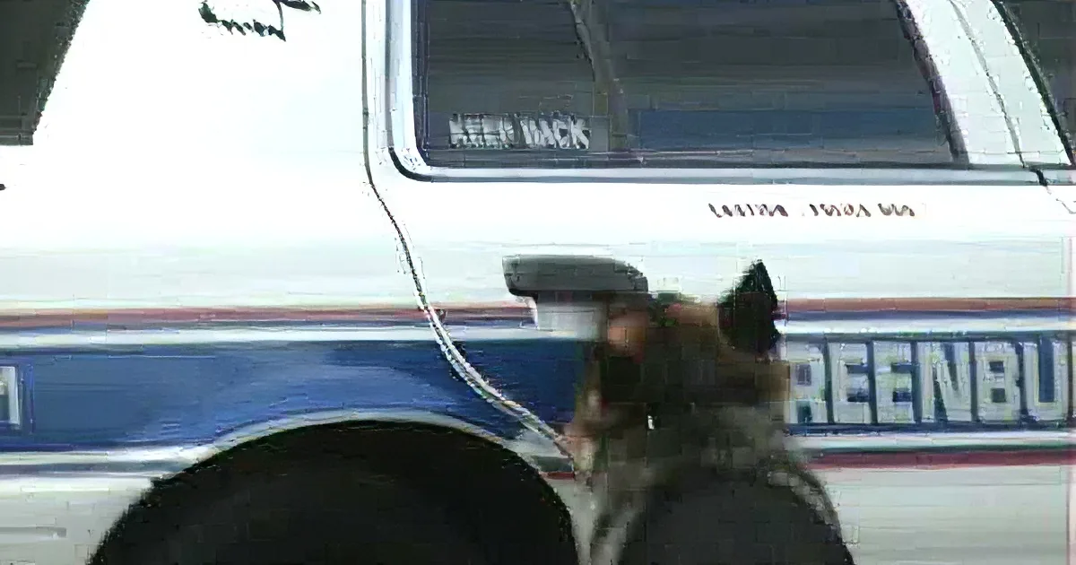 A police car with "KEEP BACK" and "LASTING PRIDE" written on it is the main subject, with blurred figures in the foreground.