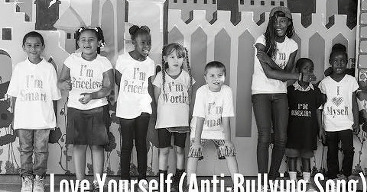 Children in white shirts with affirmations stand in front of a fence backdrop.
