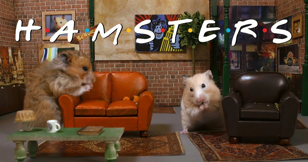 Two hamsters in a miniature living room with furniture and artwork, one eating.