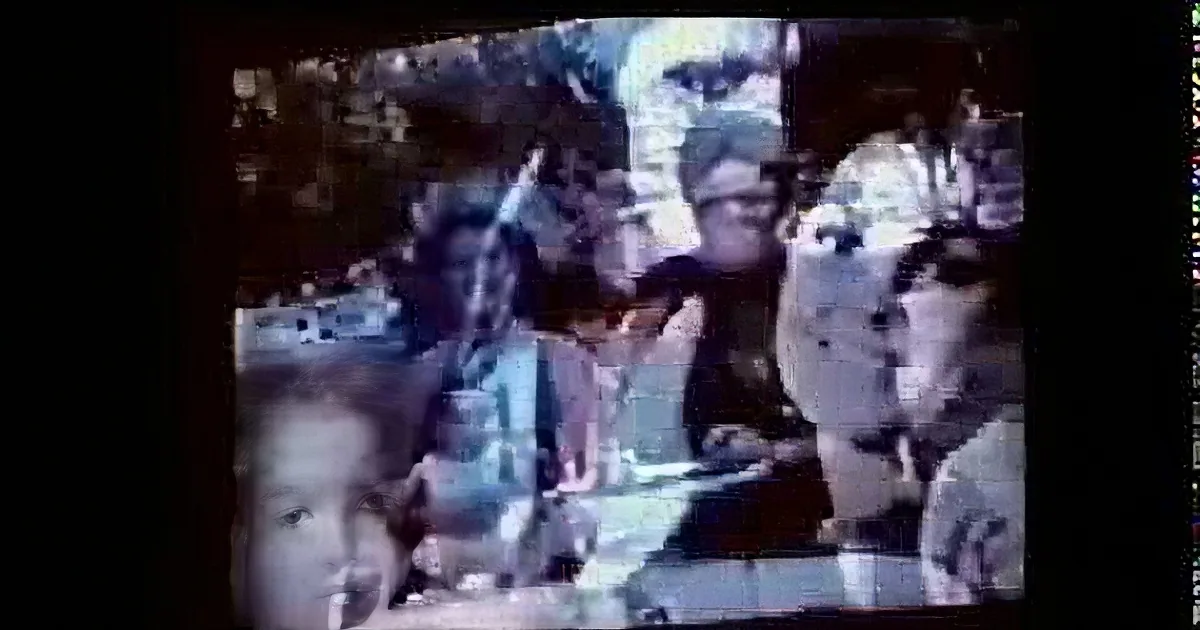 A group of people, possibly children, are gathered together, some holding objects, in a casual, outdoor setting.