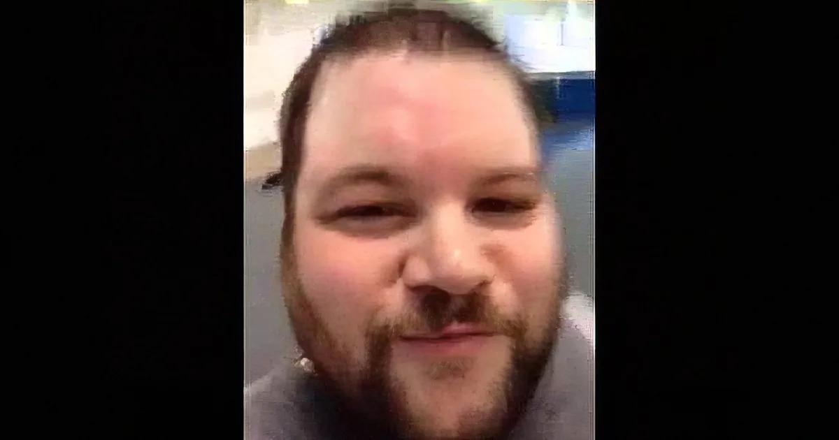 A man with a beard and short hair is smiling in a close-up shot.