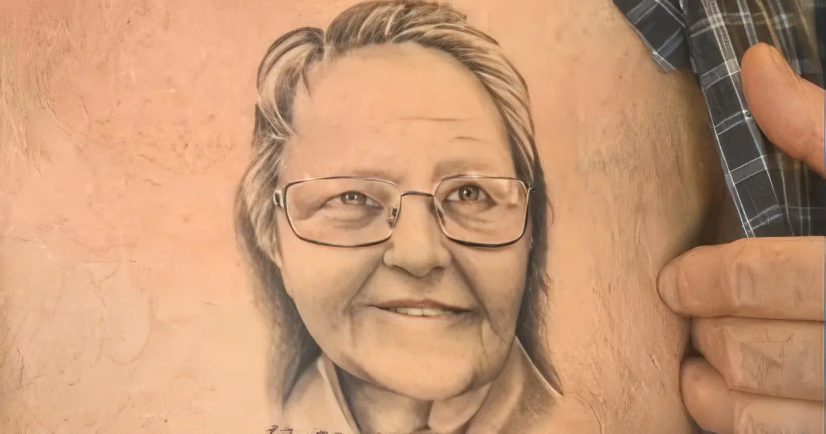 A detailed tattoo of a woman's face with glasses and a date "12-21" below it is shown on someone's arm.
