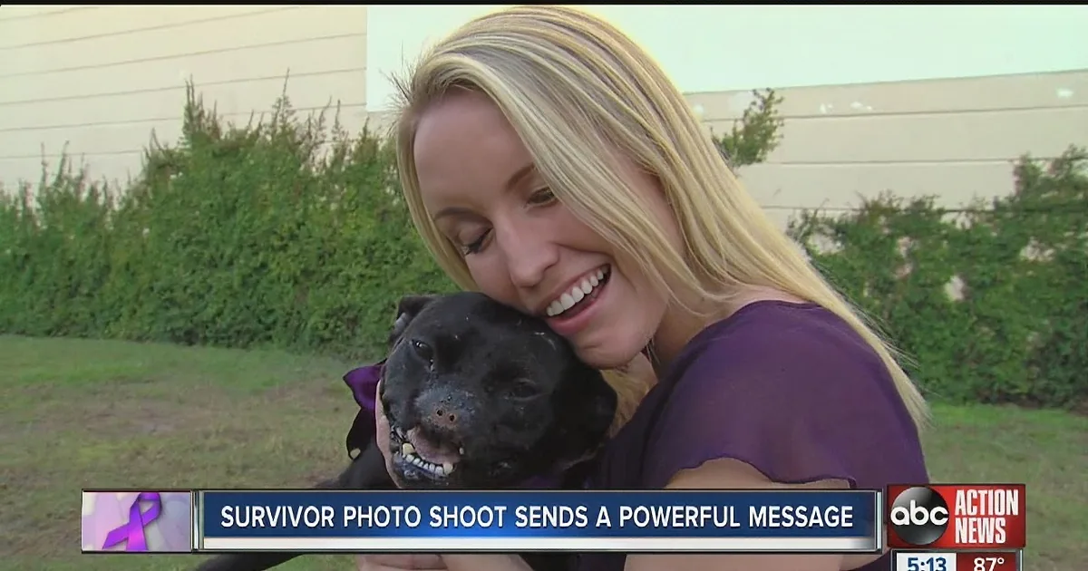A woman holds a black dog, smiling, with a news banner about a survivor photo shoot.