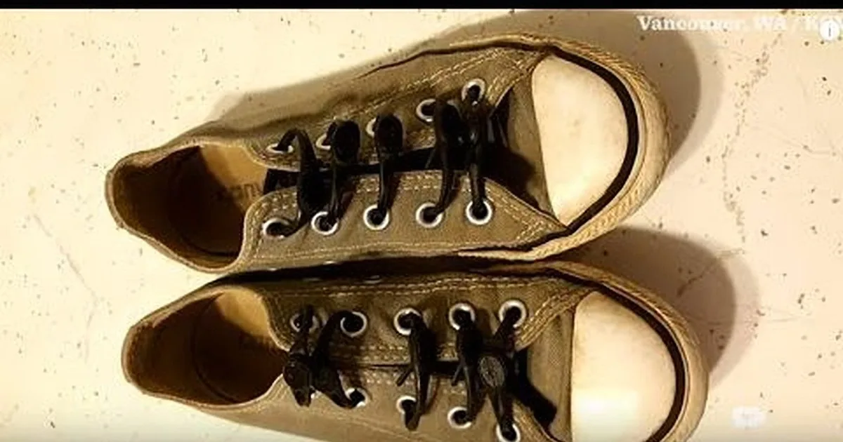 A pair of worn-out, brown canvas shoes with white soles and laces, placed on a white surface.