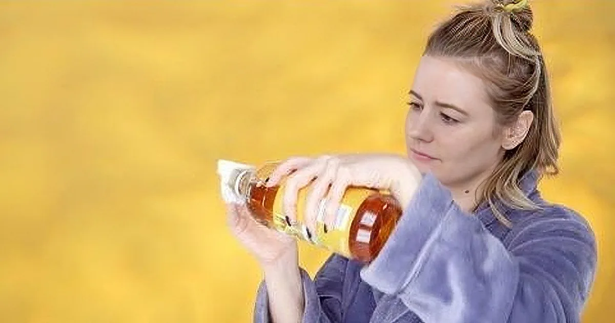 A woman in a purple outfit pours mustard from a bottle into a container.