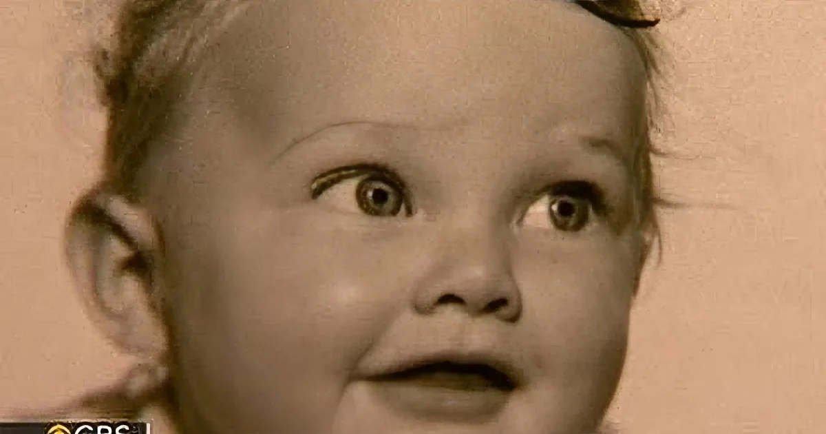A sepia-toned image of a young child with wide eyes and a curious expression.