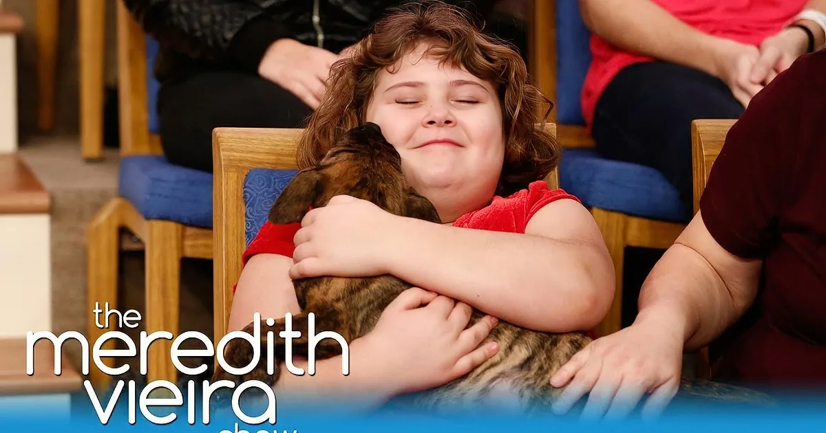 A child in a red shirt hugs a cat, smiling, with the text "The Meredith Vieira Show" in the foreground.