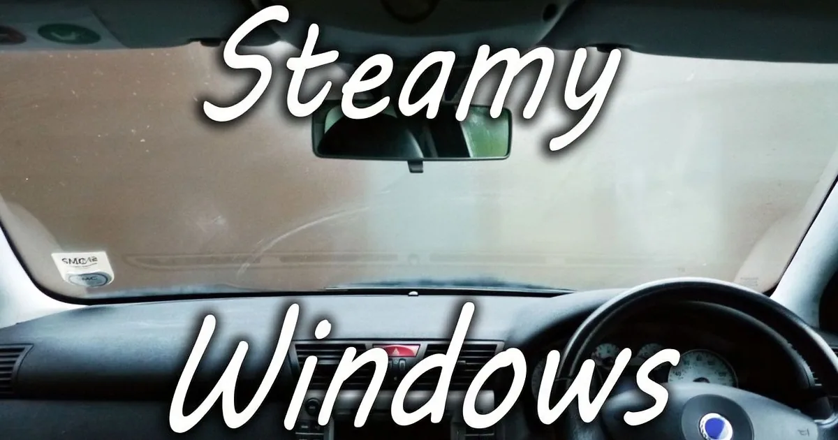 A car interior with steamy windows, dashboard, and steering wheel visible.