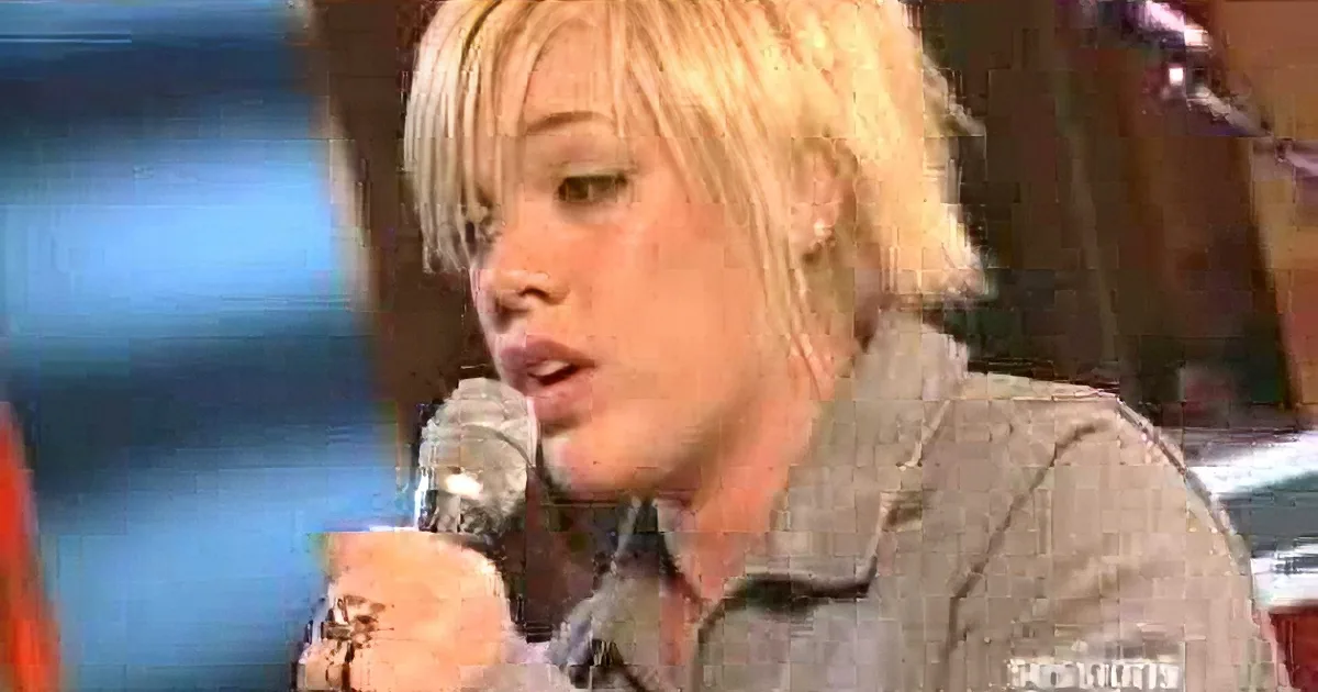 A person with blonde hair and a watch sings into a microphone, surrounded by smaller video clips.