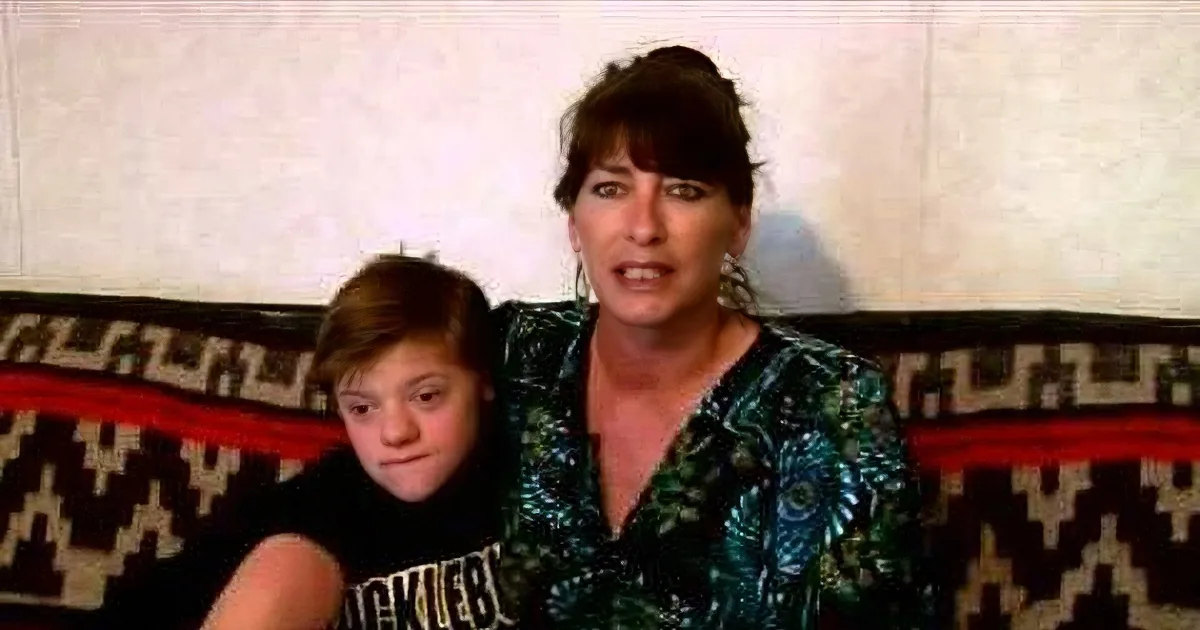 A woman and a child sit on a patterned couch, both looking forward.