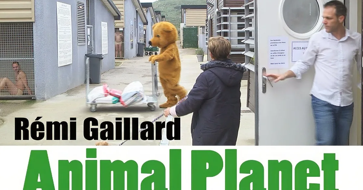 A person in a bear costume pushes a cart while another person opens a door, with a sign reading "Animal Planet" in the...