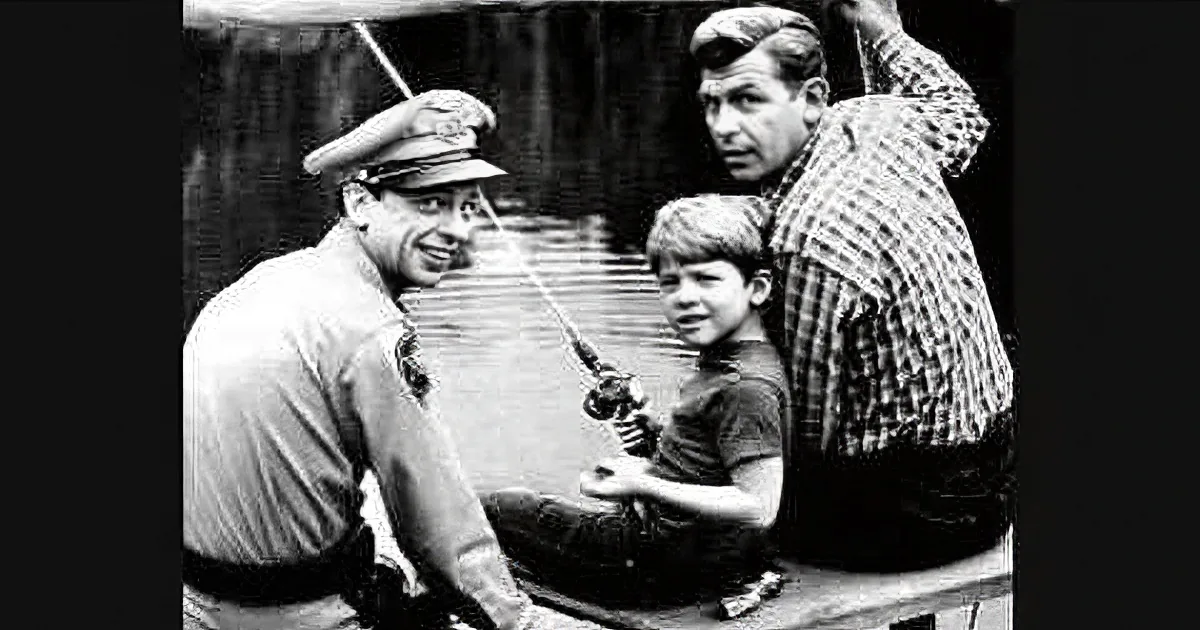 A man in a uniform and a boy fishing together, another man in a plaid shirt leans in, both smiling.
