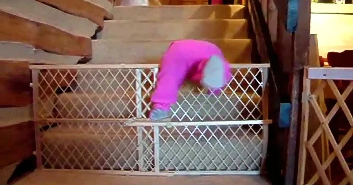 A person in a pink shirt is bent over, reaching into a white metal storage unit on a wooden staircase.