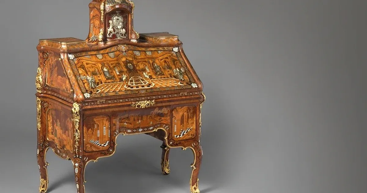 An intricately carved, ornate wooden desk with detailed embellishments and a chessboard design on its surface.