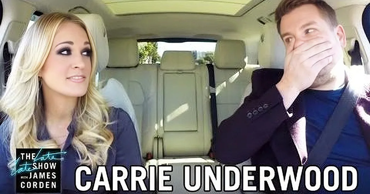 Carrie Underwood and James Corden are in a car, with Underwood smiling and Corden covering his mouth, likely reacting to...