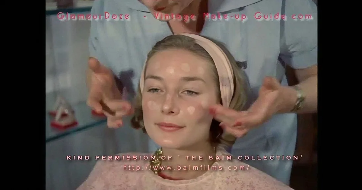 A woman receives vintage makeup application with hands gently touching her face.