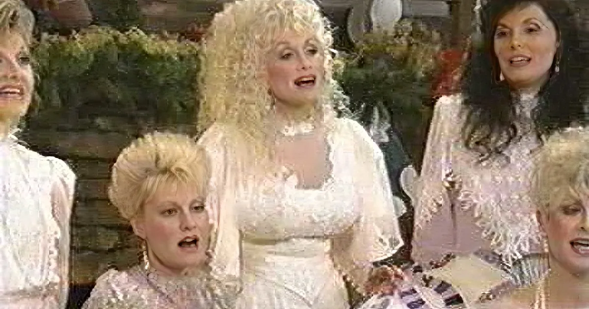 A woman in a white lace dress with long, curly hair is surrounded by others in similar attire, possibly in a performance...