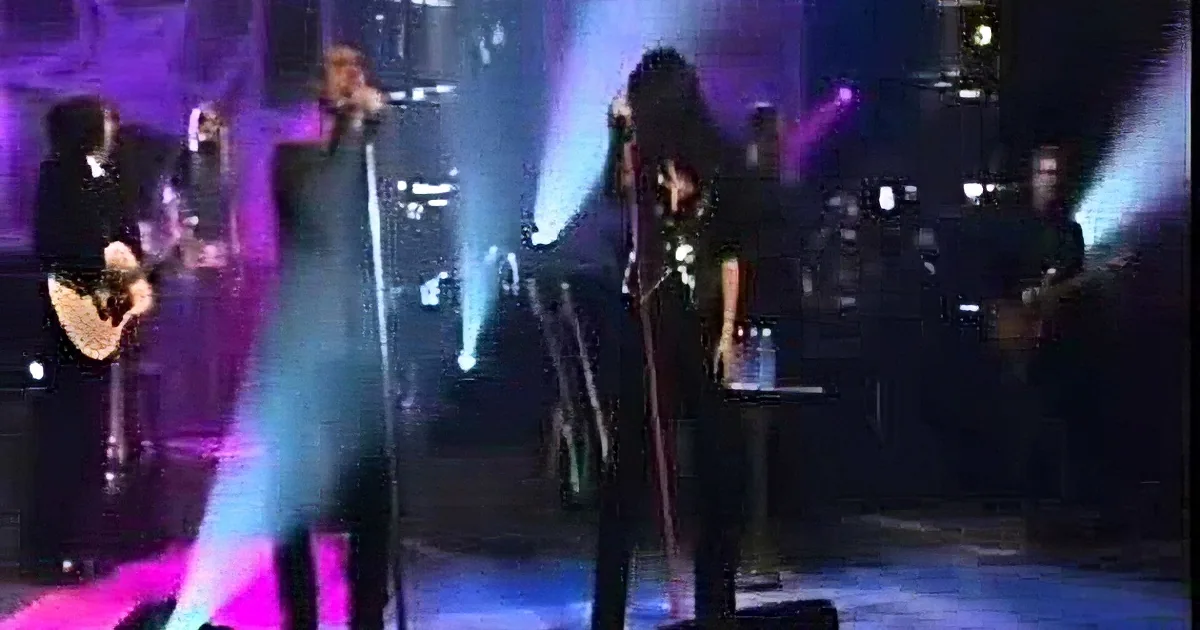 A band performs on stage with vibrant lighting, focusing on the lead singer and guitarist.