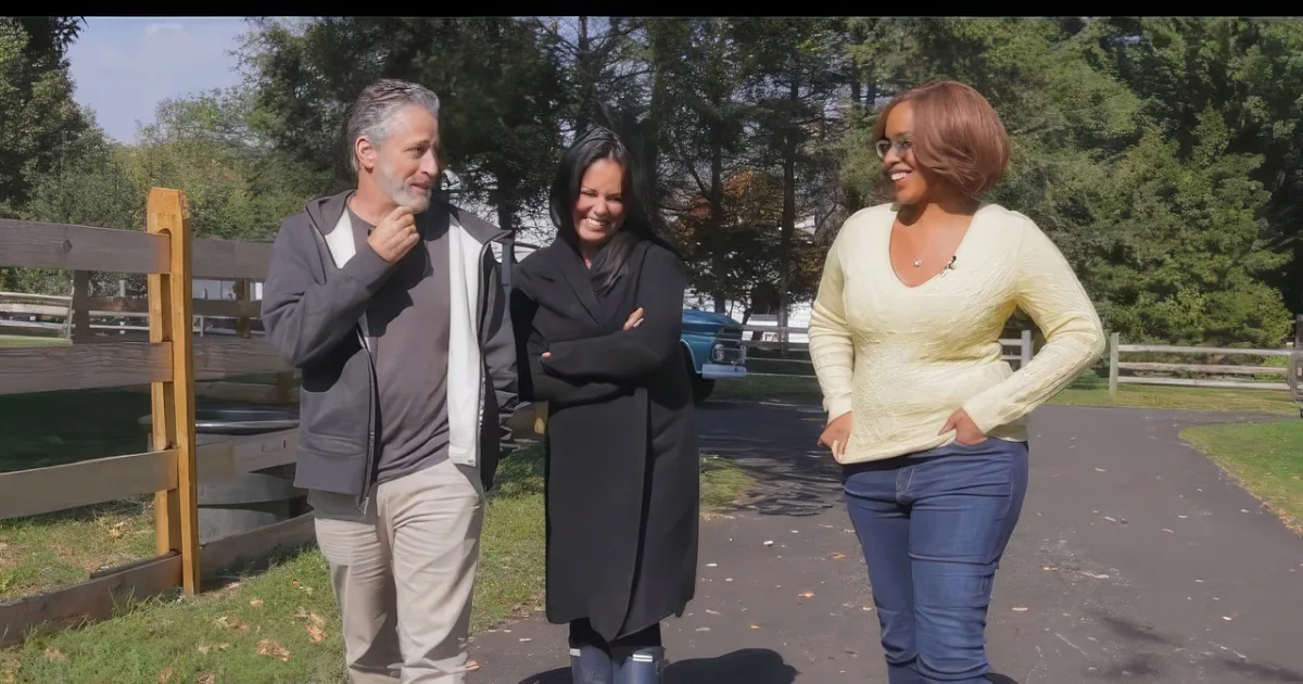 A man and two women walk together on a path, smiling and engaged in conversation.