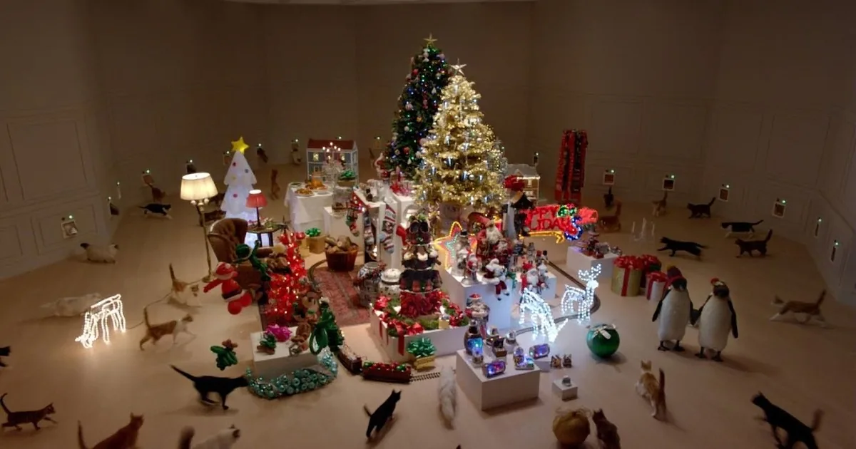 A festive Christmas scene with a large decorated tree, lights, ornaments, and numerous cats scattered around the room.