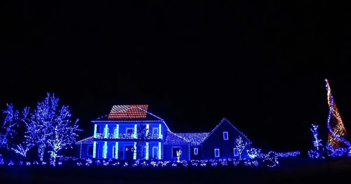 A house adorned with blue and red lights, creating a festive holiday display against a dark sky.