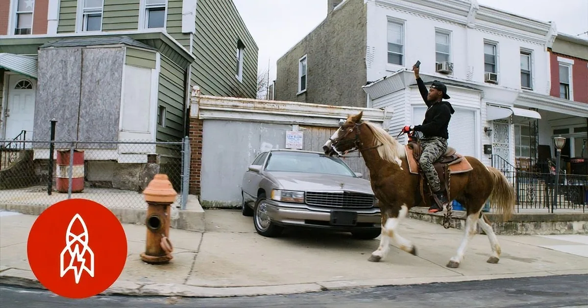 A person rides a horse on a sidewalk, holding a phone, with a car and buildings in the background.