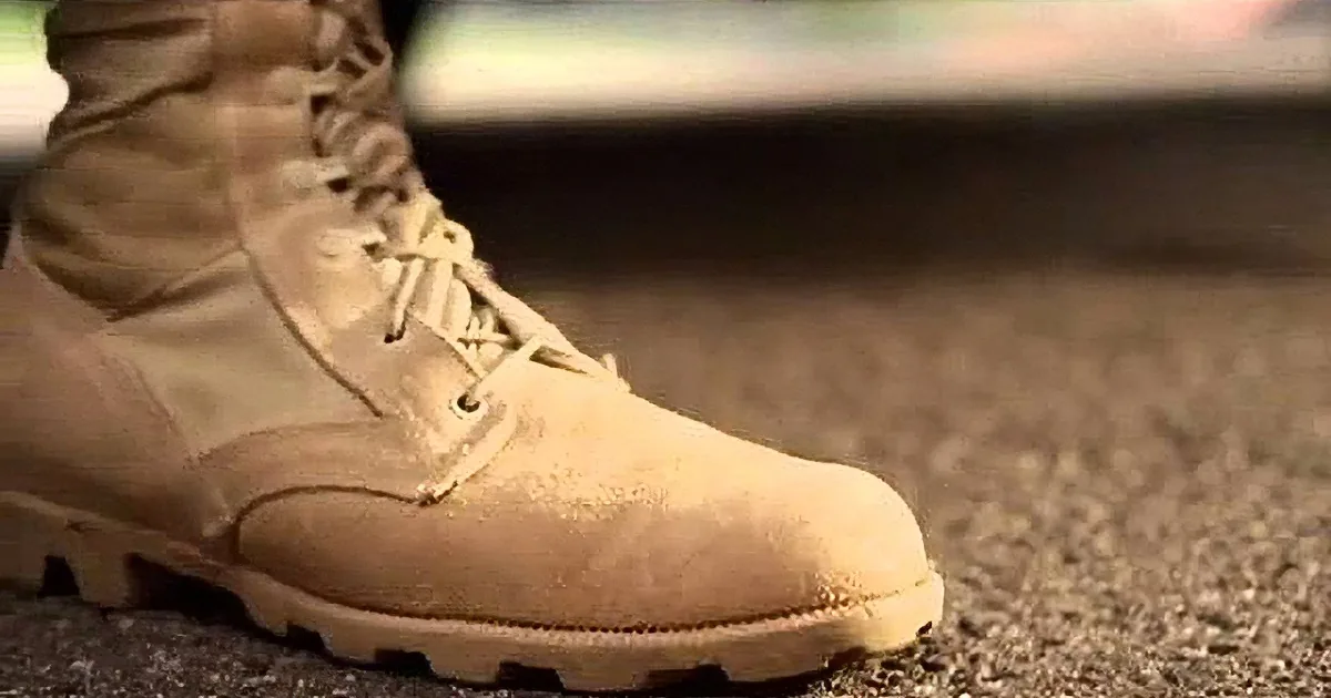 A close-up of a tan military-style boot with a rugged sole and laces.
