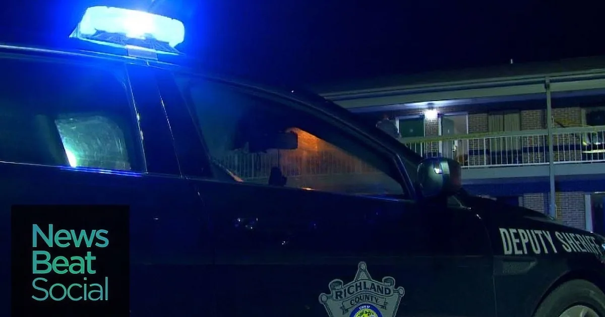 A Richland County Deputy Sheriff's car with blue lights is parked outside a building at night.