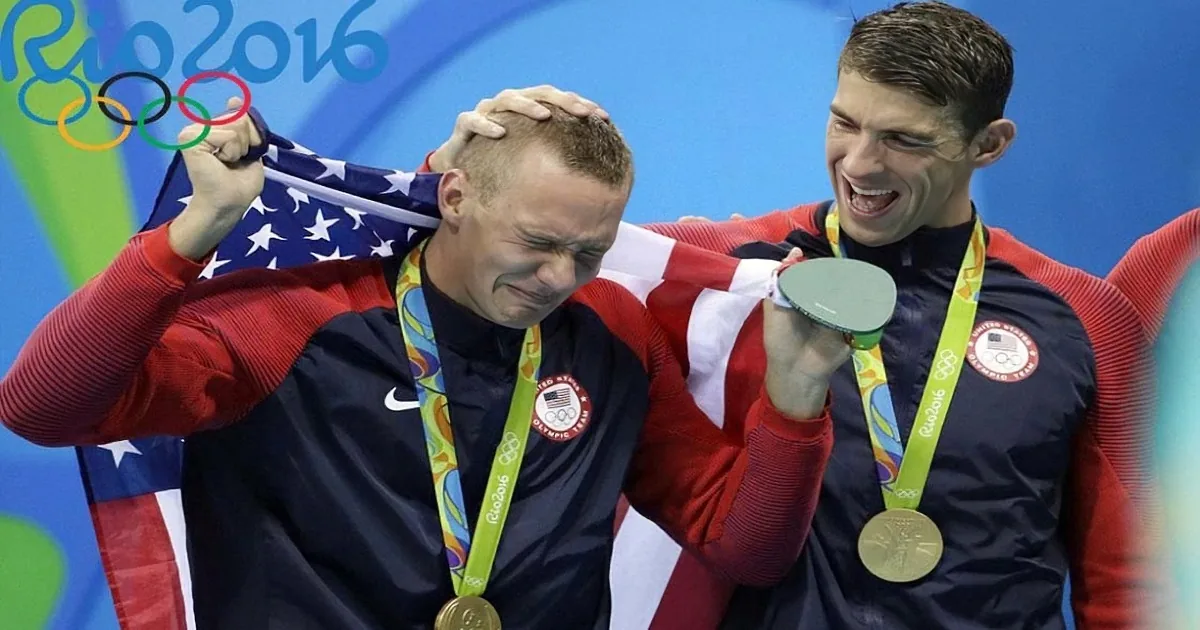 Two Olympic swimmers celebrate with gold medals and the U.S. flag at Rio 2016.