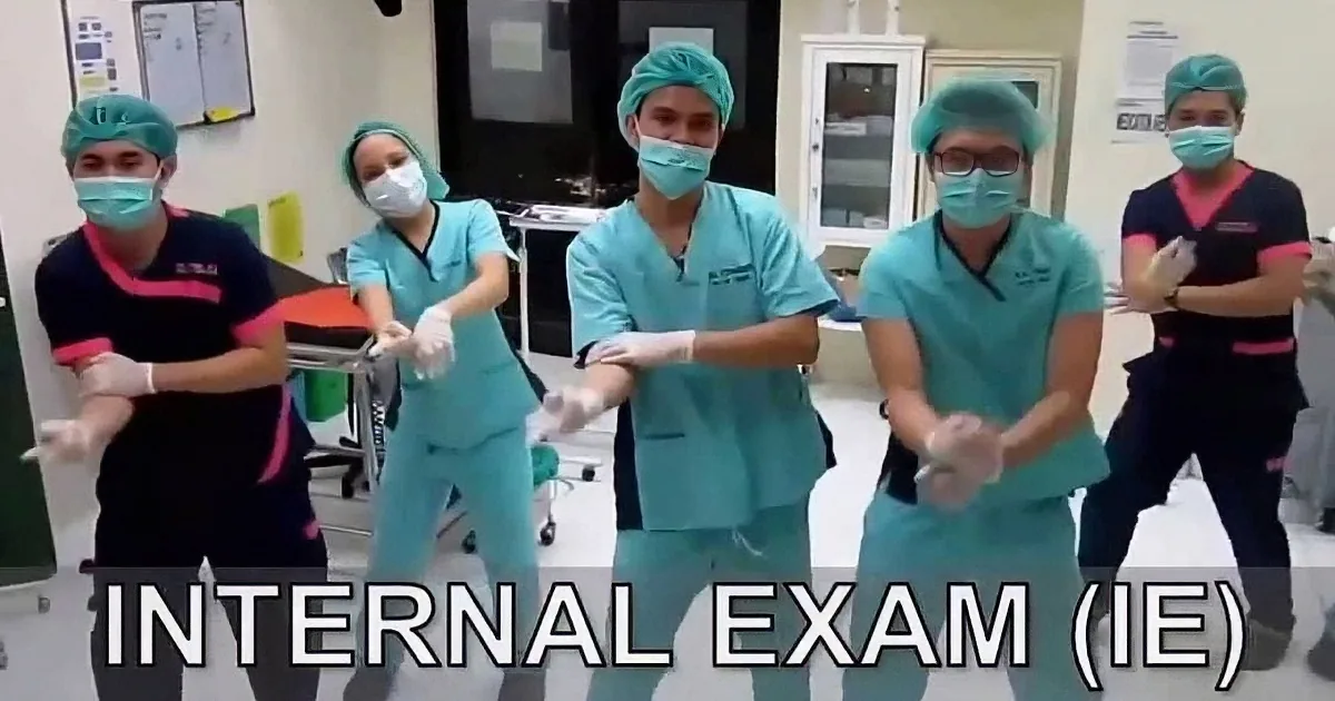 Medical professionals in scrubs and masks perform a synchronized dance in a clinical setting.