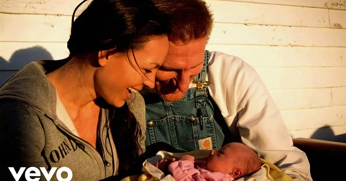 A couple holds a newborn baby wrapped in a blanket, smiling warmly.