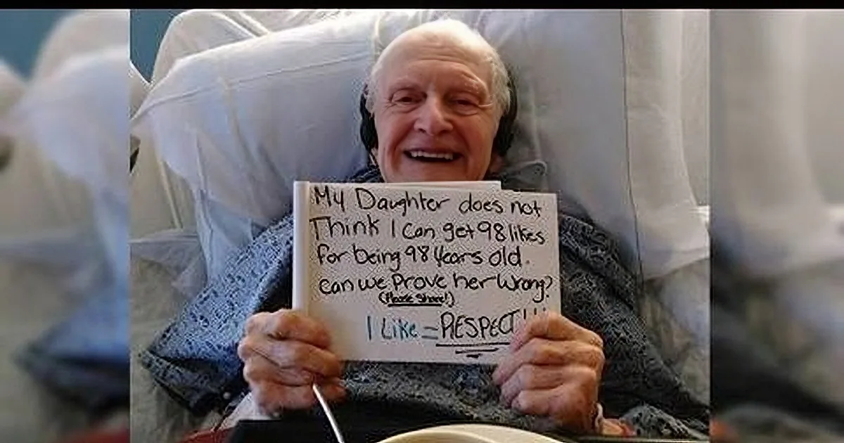 An elderly man in a hospital bed holds a sign expressing disbelief about his age and seeking proof of his youth.