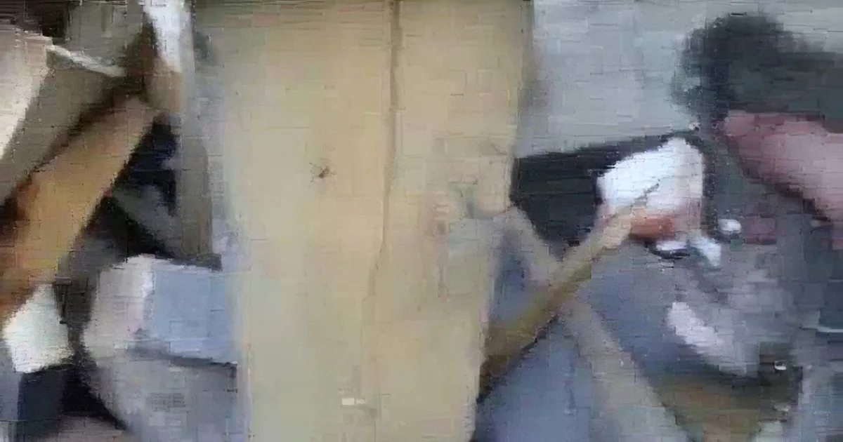 A hand holds a tool near a wooden surface with visible cracks and debris.