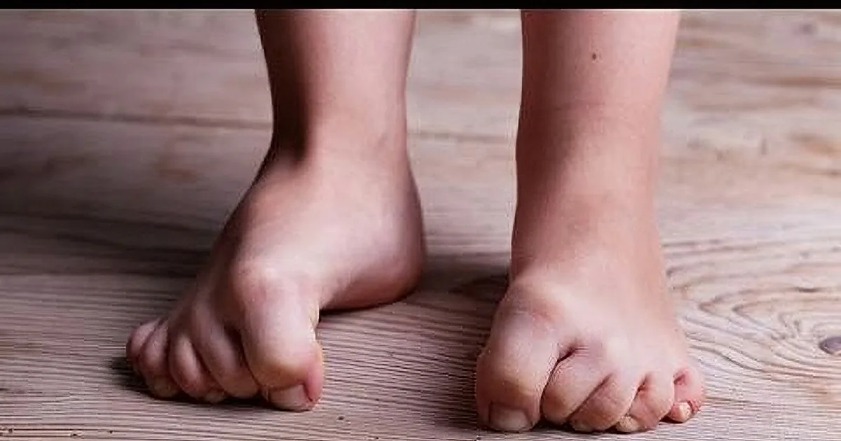 A close-up of a person's bare feet standing on a wooden floor.