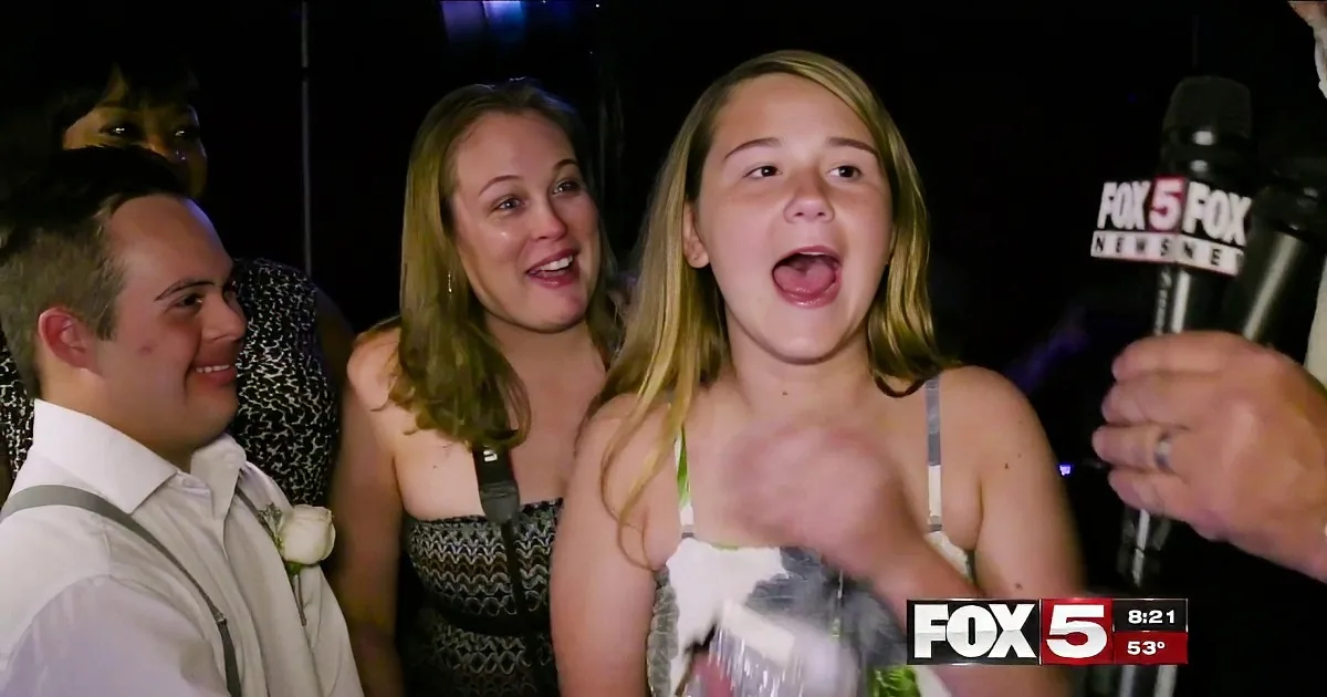 A young woman is being interviewed by a reporter at what appears to be a party or event.
