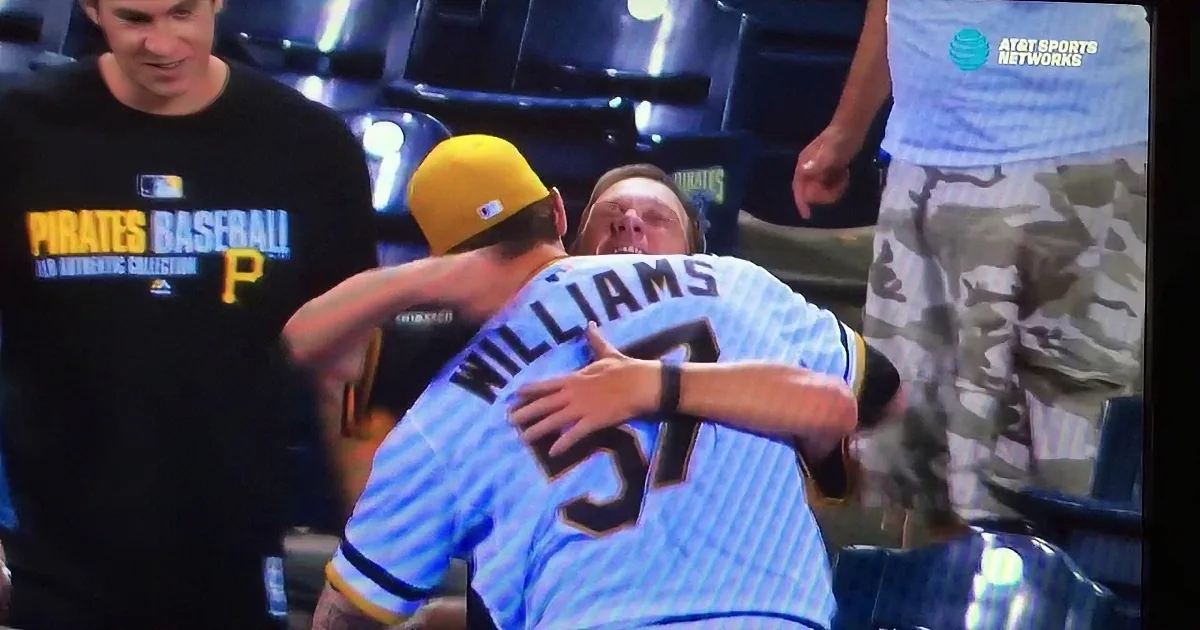 A baseball player in a blue uniform with "Williams" on the back is being embraced by another player in a yellow cap.
