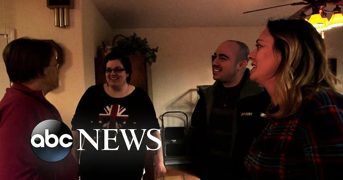 A group of four people is gathered indoors, smiling and engaged in conversation.