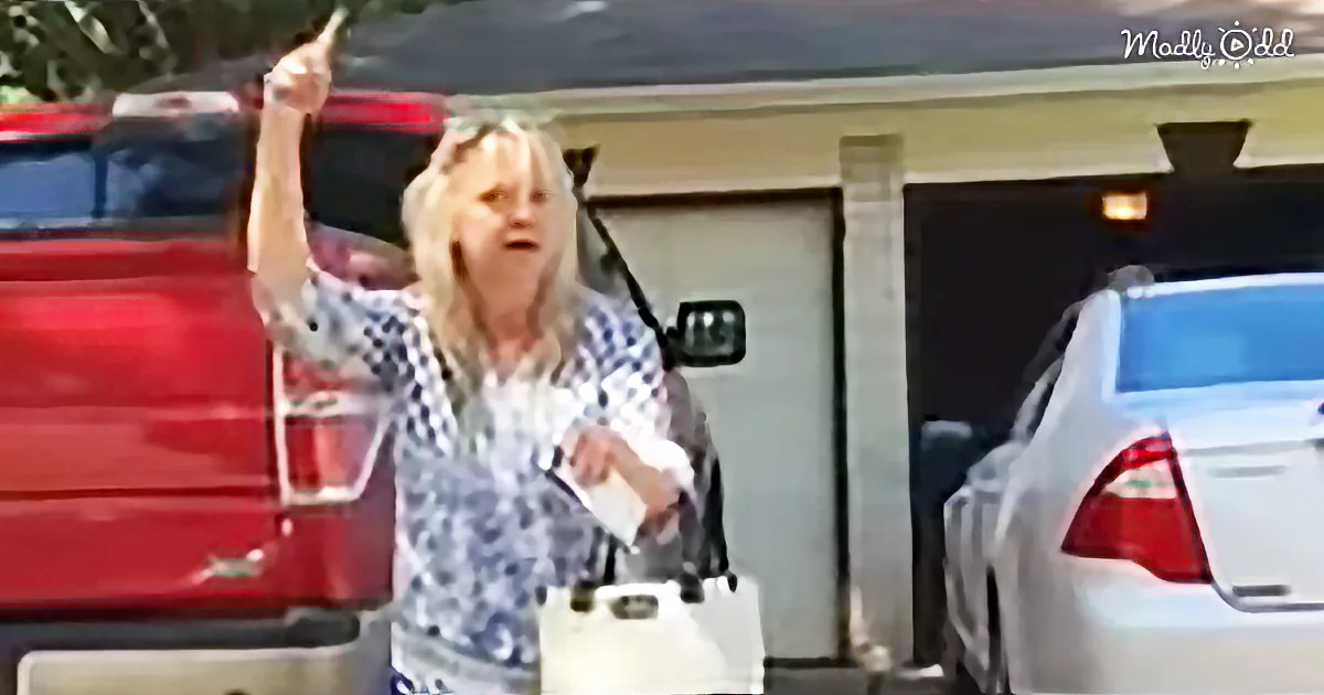 A woman with blonde hair, wearing a checkered shirt, raises her arm while holding a white bag, standing near a red truck...