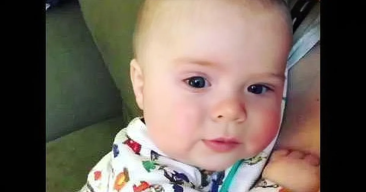 A baby in colorful pajamas looks directly at the camera with a curious expression.