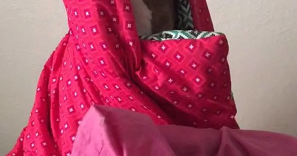A red patterned fabric draped over a person, partially covering their body.